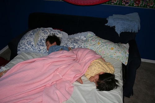 Siblings sleeping in bed