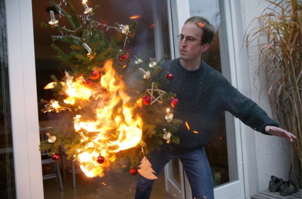 Man is running with a burning christmas tree out of the house.