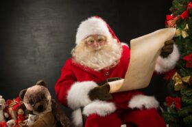 Portrait of happy Santa Claus reading Christmas letter or wish l