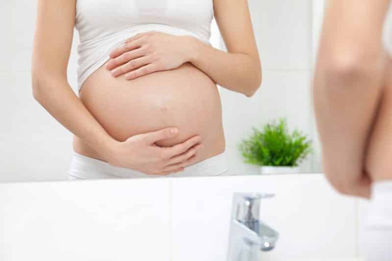 pregnant woman looking in mirror