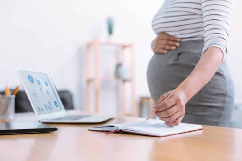 woman holding pregnant stomach at work