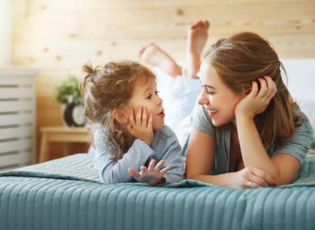 mom talking to daughter on bed