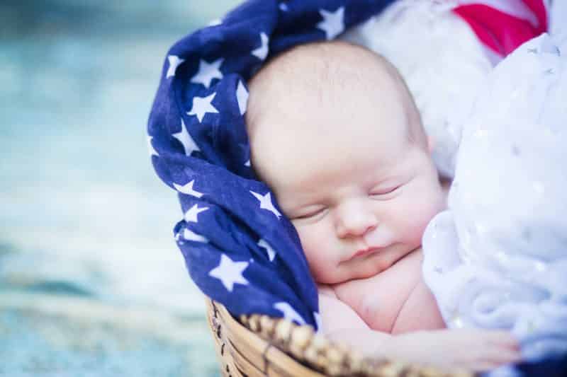 Newborn baby girl in basket surrounded by patriotic scarves